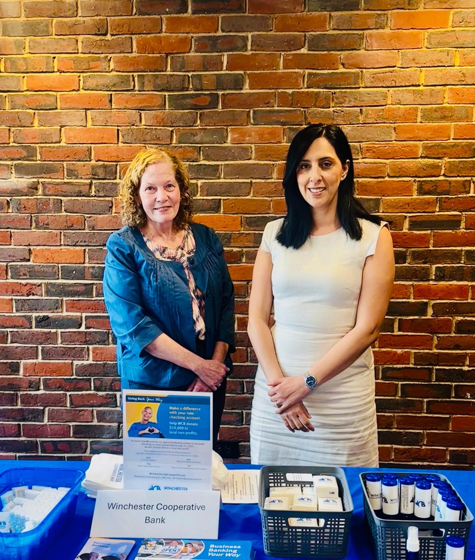 two women standing at a table with a blue tablecloth