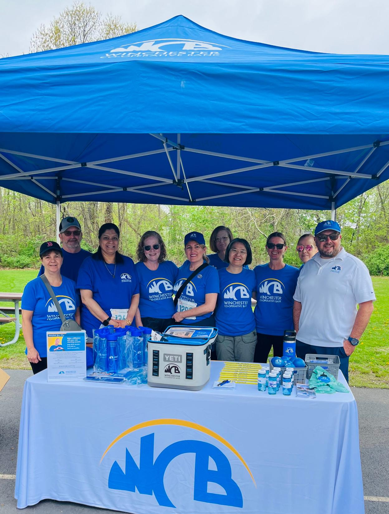 Group of employees gathering in front of table under tent