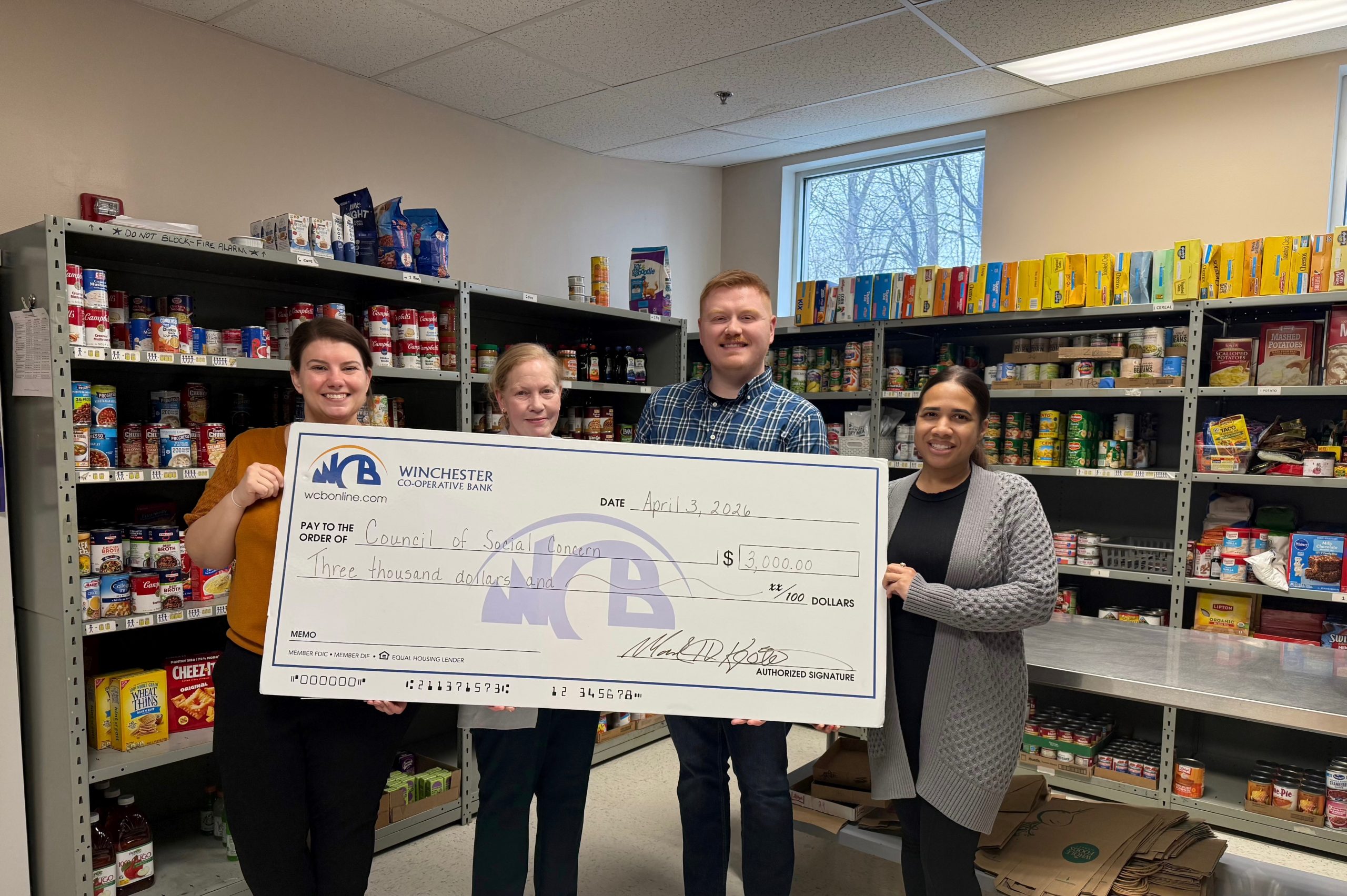 a group of people holding a big check and food items in the background