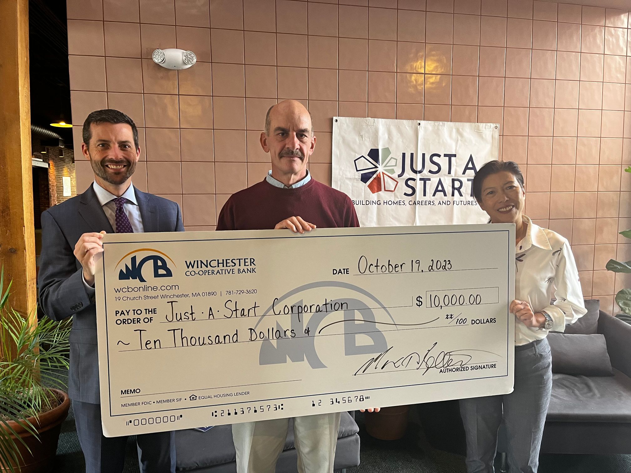 Three people pictures with a big check from the Bank