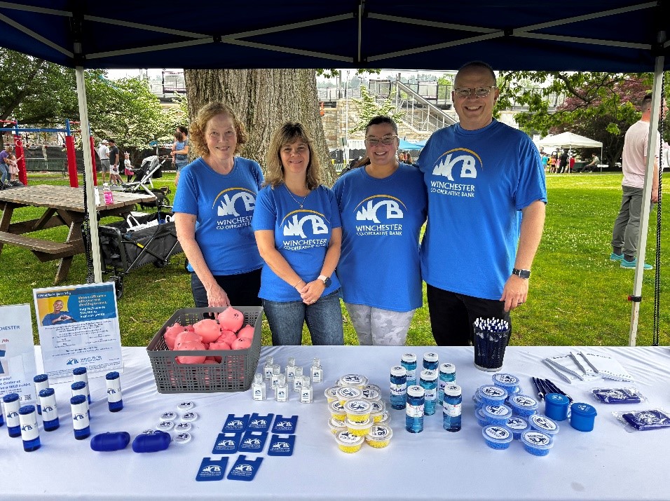 4 WCB employees in their tshirts standing behind booth
