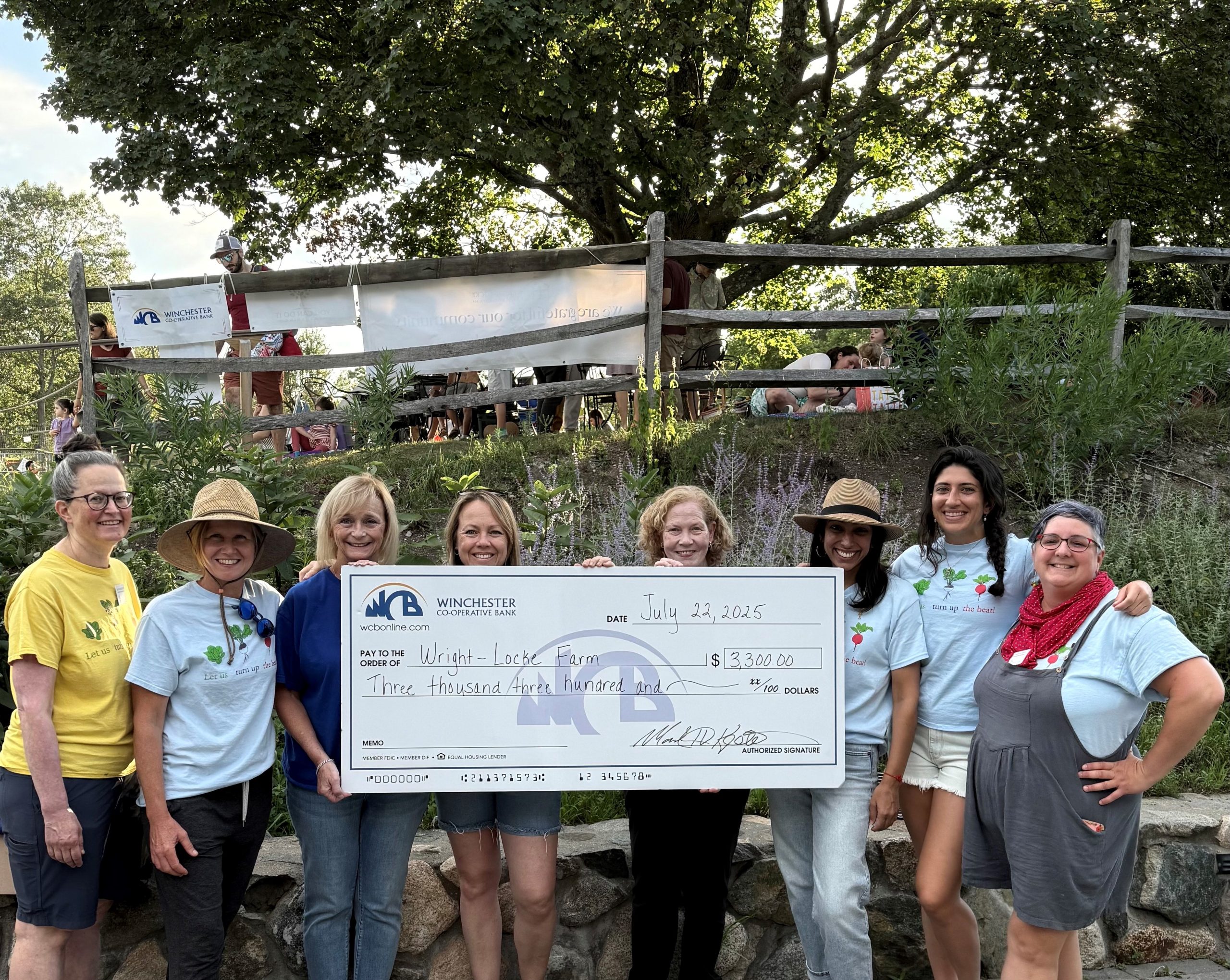 Group from Wright Locke Farm standing with WCB employees with big donation check for Family concerts
