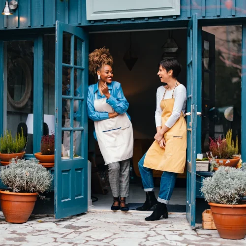 Two woman business owners standing by an open door.