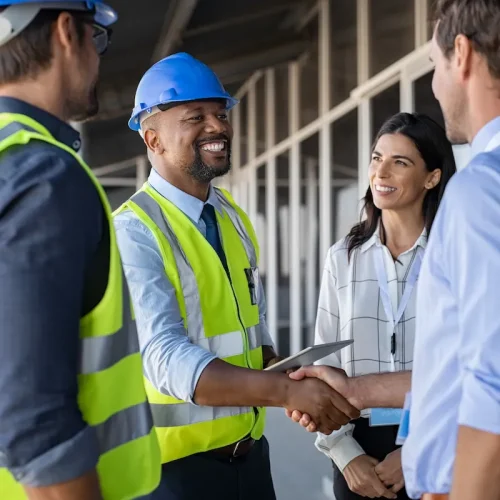 Business man on construction site wearing safety vest and blue hard hat.